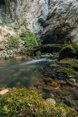 Famous old stone bridge in the karst caves of Rakov Skocjan area. Caves, underground river, depresions and skink holes of Natural park Rakov Skocjan Gorge, Slovenia. Small stone bridge over a stream.