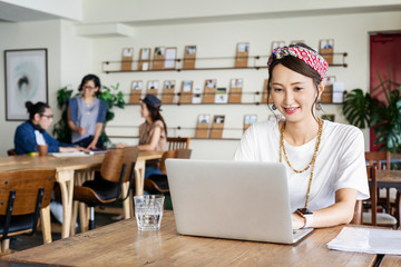 Group of young Japanese professionals working on laptop computers in a co-working space.