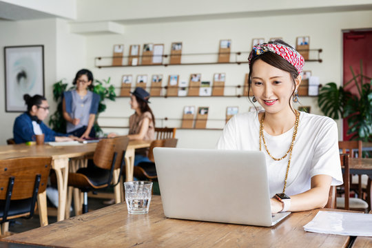 Group of young Japanese professionals working on laptop computers in a co-working space.
