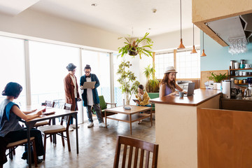 Group of young Japanese professionals working on laptop computers in a co-working space.