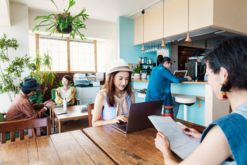 Group of young Japanese professionals working on laptop computers in a co-working space.