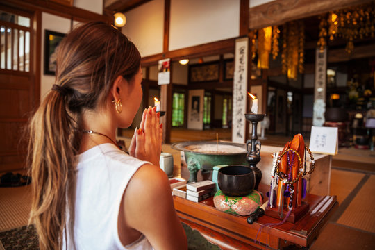 Two Japanese women kneeling in Buddhist temple, praying.