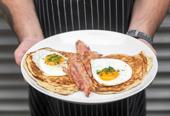 Cook's hands with salted waffles, bacon and eggs