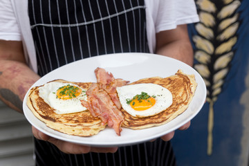 Cook's hands with salted waffles, bacon and eggs
