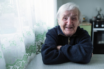 Elderly woman portrait near window in the house.