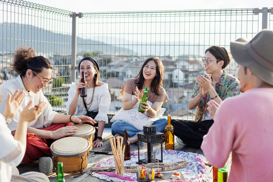 Group of young Japanese men and women standing on a rooftop in an urban setting.