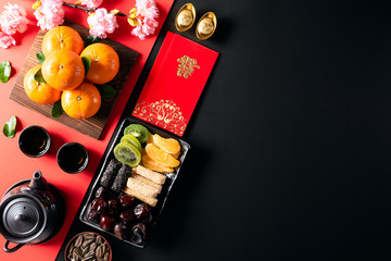 Chinese new year festival decorations pow or red packet, orange and gold ingots or golden lump on a black background. Chinese characters FU means fortune good luck, wealth, money flow.