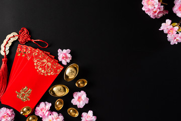 Chinese new year festival decorations pow or red packet, orange and gold ingots or golden lump on a black background. Chinese characters FU means fortune good luck, wealth, money flow.