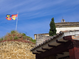 Obraz premium Flag on the hill with old church on the road to Santiago de Compostela, Camino de Santiago, Way of St. James, Journey from Poblacion de Campos to Carrion de los Condes, French way, Spain