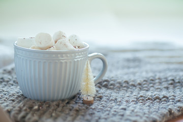 gray cup of coffee morning before Christmas. New Year's background with small white Christmas tree.