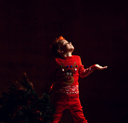 Boy kid catches snowflakes with his palm holding in one hand a Christmas tree.