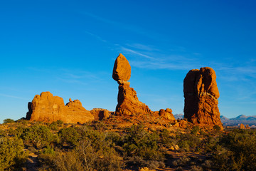 Balancing Rock stands tall against a dark blue sky in the sunset light.