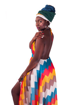 Studio Fashion Portrait Of Young African Woman In Summer Dress And Ethnic Head Wrap. Isolated White Background.