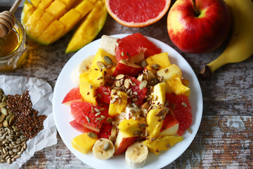 Selective focus. Fresh juicy fruit salad on a plate with mango, grapefruit and seeds. Healthy food. Vegan diet.