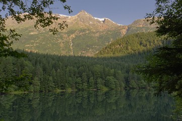 Snow-capped mountain peak above a mirror flat reflecting lake