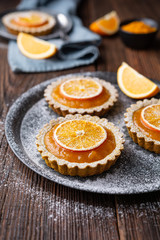 Whole-wheat turmeric tartlets filled with apricot jam, decorated with dried oranges, topped with powdered sugar