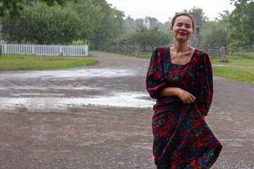 Fototapeta premium happy young Ukrainian woman is dancing under the rain in a rural farm area in summer