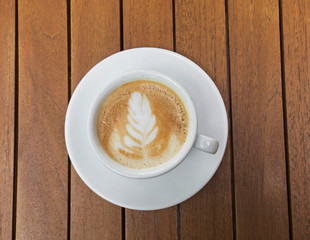Cup of creamy coffee on a wooden table
