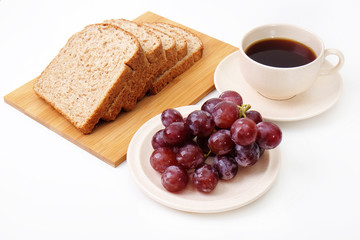 Whole grain bread and grapes serve with a cup of coffee..