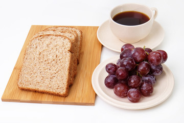 Whole grain bread and grapes serve with a cup of coffee..