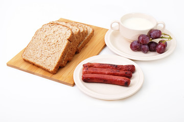 Whole grain bread, sausages and grapes serve with milk..