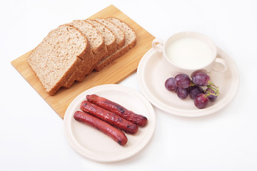 Whole grain bread, sausages and grapes serve with milk..