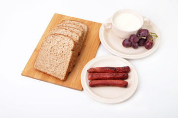 Whole grain bread, sausages and grapes serve with milk..