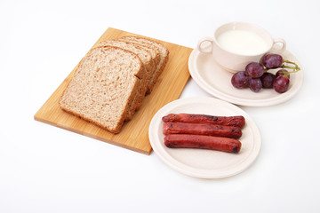 Whole grain bread, sausages and grapes serve with milk..