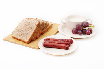 Whole grain bread, sausages and grapes serve with milk..
