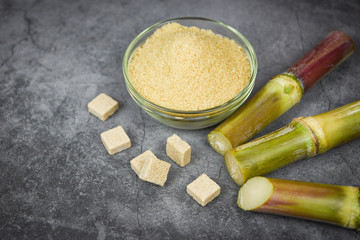 sugar cubes sugar cane and brown sugar in bowl and the dark table background