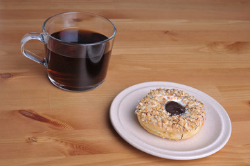 A donut with peanut as a topping on top of wooden table.