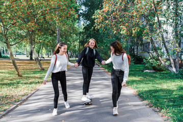 3 girls girlfriends teenagers, ride skateboard, day city street, happy smile, rejoice have fun after school college. Emotions relaxation entertainment, walk casual wear. Sneakers jeans sweater.