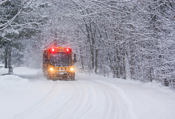 School Bus Travelling on a Snow Covered Rural Road with Stop Lights Flashing