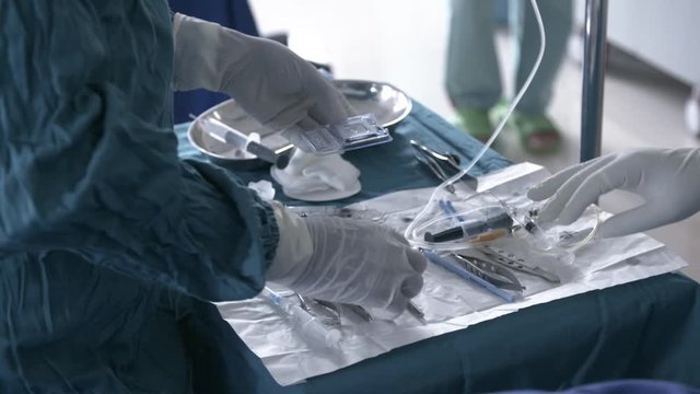 Nurse preparing a new lens for eye surgery and handing it over to the doctor
