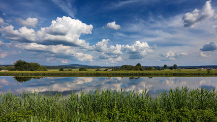 Dramatic clouds in blue sky reflect in the water of the the Rhine-Main-Danube Canal near Forchheim, Germany. 