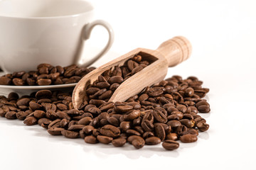 Holzschaufel mit Kaffeebohnen und Tasse vor weißen Hintergrund