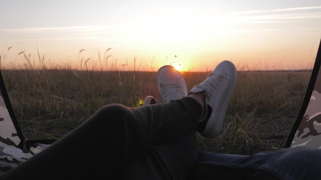 Close up legs rest in tent at sunset. Happy couple inside tent camping in landscape mountain. Travel, love, nature and excursion concept.