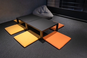 Beautiful black wooden table with yellow, orange gray colorful cushion in living room interior decoration Japanese style