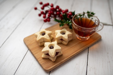 Christmas shortbread star cookies with strawberry jam. Festive atmosphere holiday pastry baking concept. Cookies and tea for Santa
