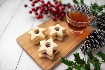 Fototapeta premium Christmas shortbread star cookies with strawberry jam. Festive atmosphere holiday pastry baking concept. Cookies and tea for Santa