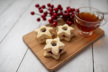 Christmas shortbread star cookies with strawberry jam. Festive atmosphere holiday pastry baking concept. Cookies and tea for Santa