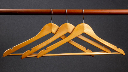 Empty wooden clothes hanger hanging on a dark background. Accessories and items for storing clothes.