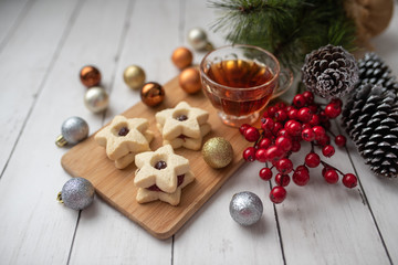 Christmas shortbread star cookies with strawberry jam. Festive atmosphere holiday pastry baking concept. Cookies and tea for Santa