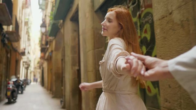 Closeup woman holding man hand in old city street. Pov of romantic couple hands