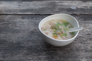 Pork porridge in a white cup on wooden table