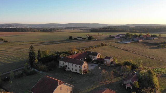 Aerial drone view of manor house at small village surrounded by rural landscape at golden hour