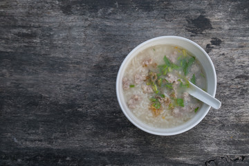 Pork porridge in a white cup on wooden table