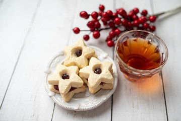 Christmas shortbread star cookies with strawberry jam. Festive atmosphere holiday pastry baking concept. Cookies and tea for Santa
