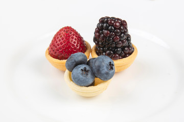 Blackberry, blueberry and strawberry in a waffle basket on a white background. Vitamins and wholesome foods