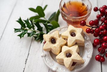 Christmas shortbread star cookies with strawberry jam. Festive atmosphere holiday pastry baking concept. Cookies and tea for Santa